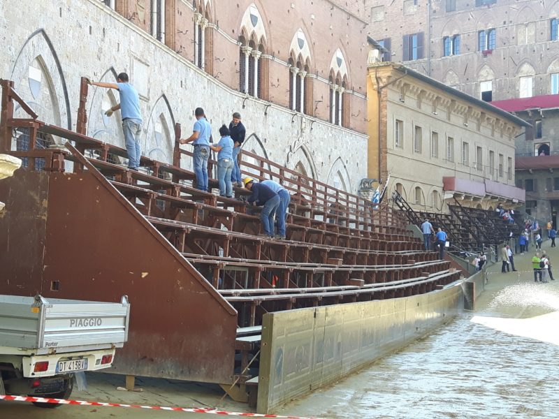 Montaggio del palco delle comparse, operai al lavoro  per recuperare dopo il maltempo